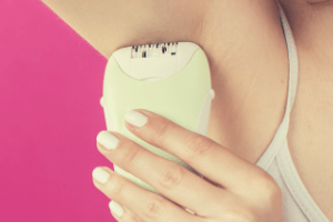 Woman removing under arm hair with an epilator.